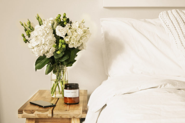 cama con mesita con flores y vela